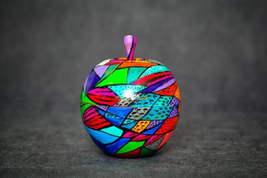 Karanlık bir arka plan, boyalı renkler üzerinde dekoratif ahşap elma. Konu el yapımı