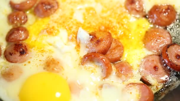 Scrambled eggs with sausages fried on a frying pan, close-up — Stock Video