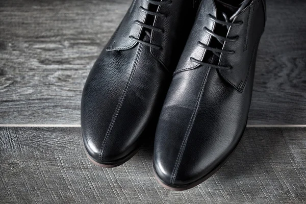 Nuevos zapatos de cuero negro de los hombres en piso de madera — Foto de Stock