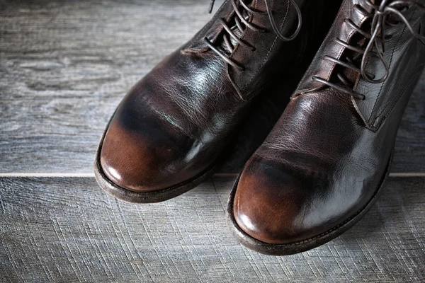 Braune Lederschuhe auf einer Holzoberfläche. wunderschöne Stiefel im Grunge-Stil, Draufsicht — Stockfoto