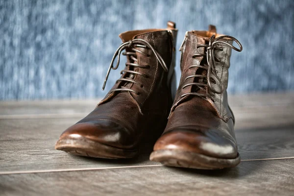 Primer plano de un nuevo par de zapatos de vestir de cuero marrón. botas altas frías sobre una superficie de madera — Foto de Stock