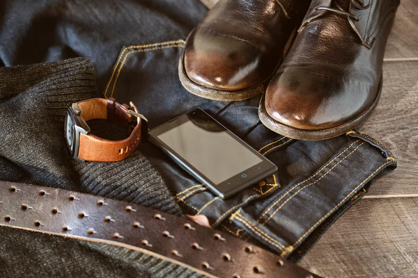 Одежда и аксессуары натюрморта - обувь, джинсы и кожаный ремень, наручные часы, смартфон — стоковое фото