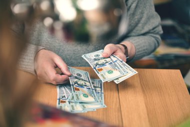 Zengin bir adam dolar sayar. el ve 100 dolar faturaları kapatın. arkasındaki adam gözetleme için. 