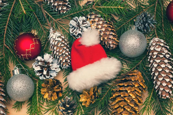 Fondo de Navidad, motivos navideños, ramas de árbol de Navidad decoradas con conos de pino y gorra de Santa Claus —  Fotos de Stock