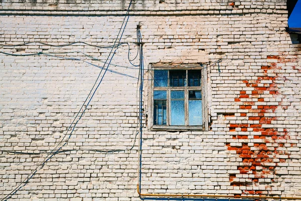 Vintage background texture of old brick walls painted in white paint. An old window. The details of the old dilapidated buildings