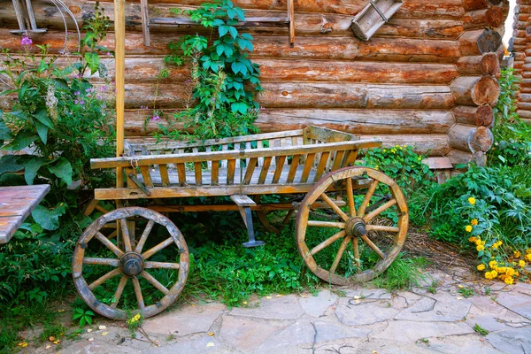 El carro de madera sobre un fondo de madera casa de madera en el pueblo —  Fotos de Stock