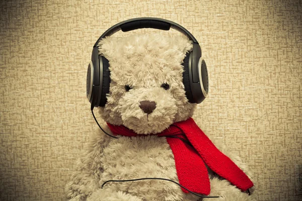Urso retrô ouvindo música em fones de ouvido. foto tonificado amarelo — Fotografia de Stock