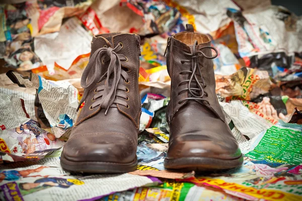 Botas de couro masculinas que estão ao lado de pedaços amassados de papel - estilo grunge. Outono de prestígio - sapatos de primavera Fotos De Bancos De Imagens Sem Royalties