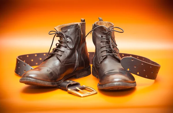 Nature morte d'automne : chaussures en cuir pour homme et ceinture en cuir avec boucle. Chaussures à la mode et ceinture marron sur fond orange — Photo