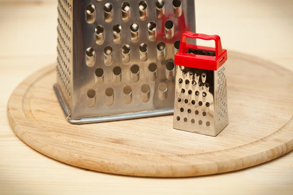 Small and large grater on wooden cutting board — Stock Photo, Image