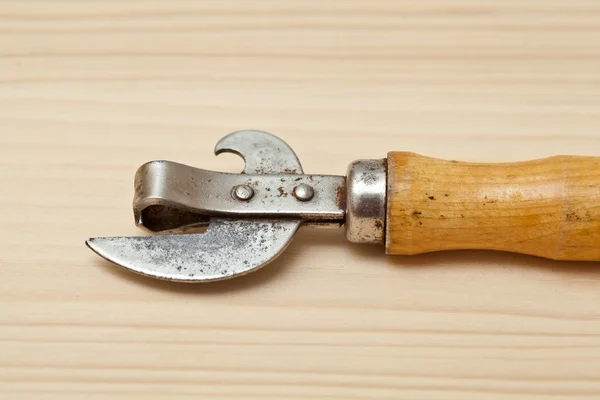 Abridor viejo para comida enlatada y cerveza en una mesa de madera — Foto de Stock