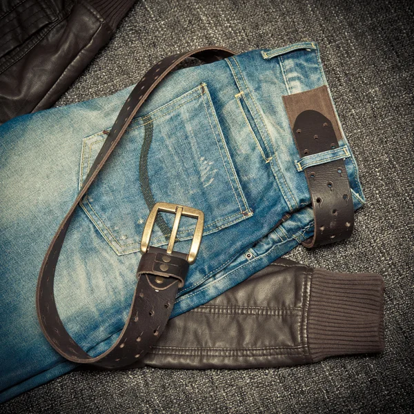 Modetrend: blauw gerafeld jeans, een leren jack en lederen riem met gesp — Stockfoto