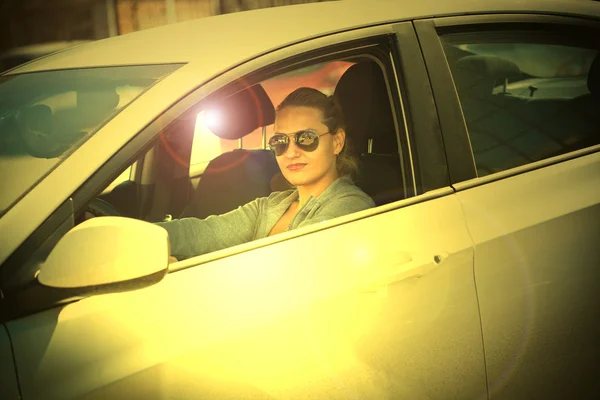 Дівчина в машині за кермом в сонцезахисних окулярах — стокове фото