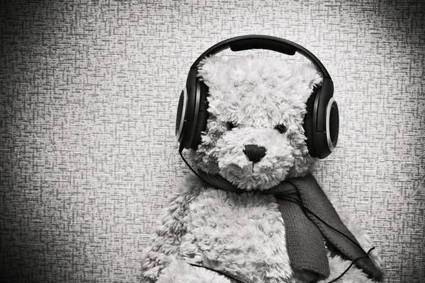 Plüsch-Teddybär hört Musik über Kopfhörer. Jahrgang verfärbt Foto — Stockfoto