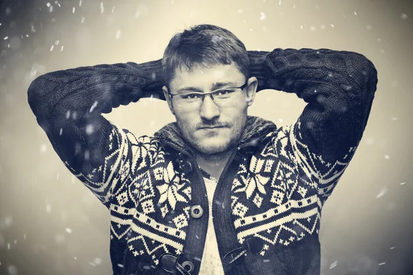 Retrato de un hombre con gafas y un suéter de moda. Invierno, nieve cae — Foto de Stock