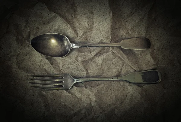 Antieke zilveren bestek - vork en false op vintage achtergrond van verfrommeld papier — Stockfoto