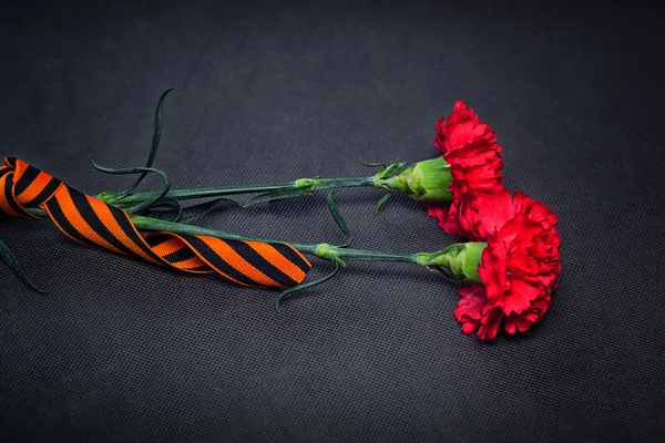 Flores de cravo e George Ribbon close-up em um fundo escuro. Dia da Vitória - 9 de maio. Jubileu 70 anos . — Fotografia de Stock