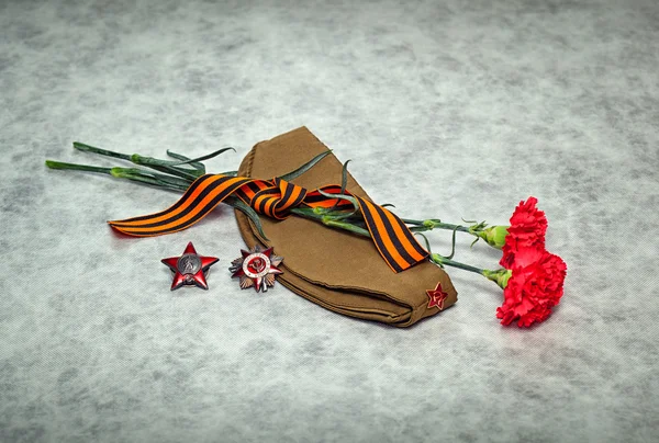 Carnation bloemen, George Ribbon, voedergewassen cap, orders en medailles. Dag van de overwinning - 9 mei. — Stockfoto