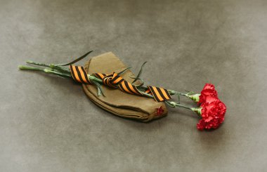 Carnation flowers, George Ribbon and military garrison cap with a red star. May 9 Victory Day