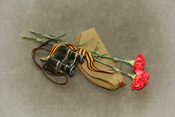 Fleurs d'oeillet, ruban George et jumelles militaires. Photo rétrospective du Jour de la Victoire le 9 mai Photo De Stock