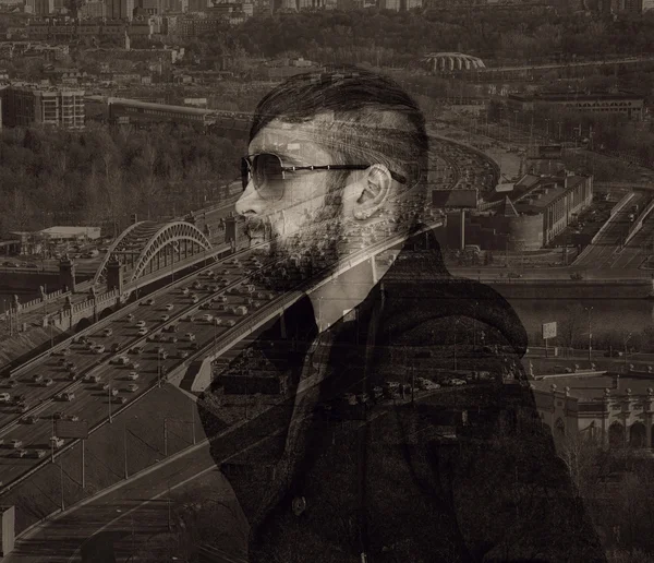 Brutal man with a beard and sunglasses on city background. Photo collage, effect of multiple exposure — Stock Photo, Image