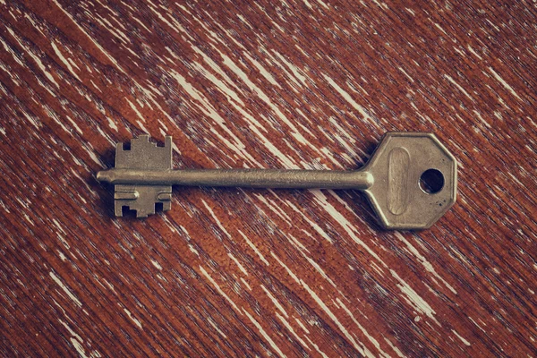 Golden key on vintage wooden surface — Stock Photo, Image