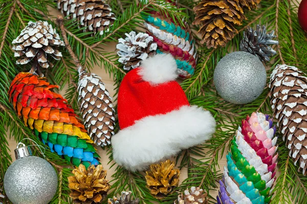 Bodegón de Navidad - ramas de abeto con conos y juguetes, un sombrero de Santa Claus —  Fotos de Stock