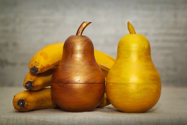 Natürliche und dekorative Früchte in einem Rahmen. Bananen und Birnen. Zierbirnenholz, handbemalte Farben — Stockfoto