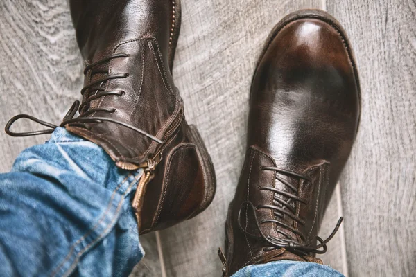 Stiefel und Jeans in Bewegung. Beine eines jungen Modemachers in Jeans und Stiefeln auf Holzboden — Stockfoto