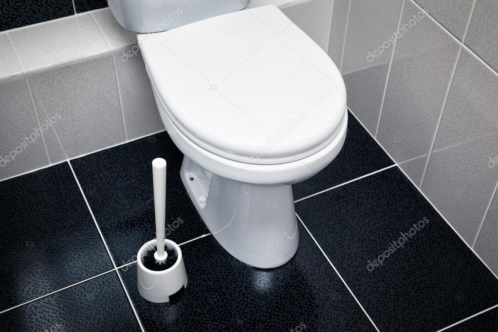 white toilet, black tiles on the floor
