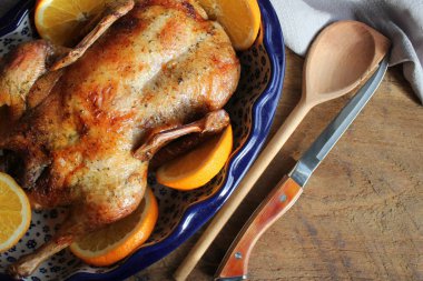 Bayram için taze portakal dilimleri ile tam çıtır altın rosto ördeği. Üst görünüm rustik ahşap arkaplan.