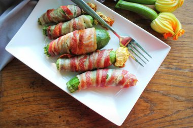 Beyaz tabakta domuz pastırmasına sarılı kızarmış kabak kızartması. .