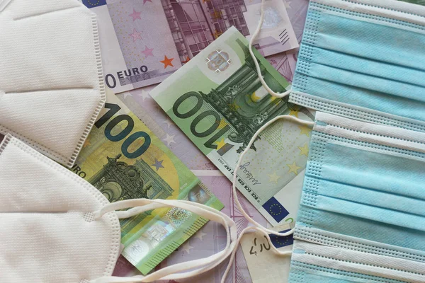 Medical face masks and money. Surgical face mask. COVID-19 Has Caused A Shortage Of Face Masks. Euro banknotes and Medical face masks.