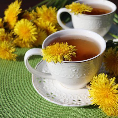 Fincanın içinde taze sarı bir çiçek olan karahindiba çayı. Vitamin içeceği. Sağlık için karahindiba bitkisi çayı.