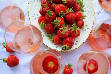 Beyaz arka planda gül şarabı ve lezzetli çilekler ile yaratıcı kompozisyon, üst görünüm .
