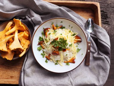 Köy ahşap bir masada bir kase lezzetli chanterelle risotto.