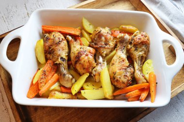 Kızarmış tavuk budu ve beyaz tavada sebze.