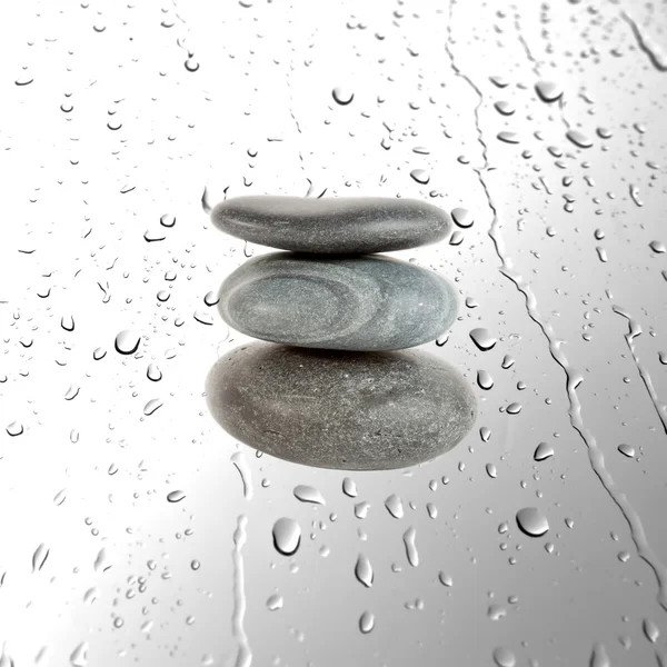 Drie grijs pebble stenen over water drops achtergrond — Stockfoto