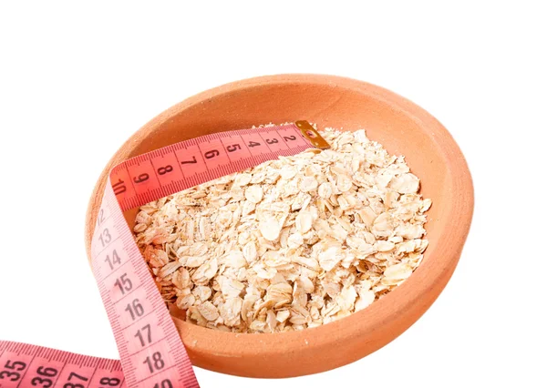 Oat flakes in ceramic bowl and Measuring tape isolated on white. — Stock Photo, Image