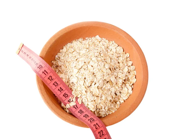 Oat flakes in ceramic bowl and meter. Diet food for breakfast. — Stock Photo, Image