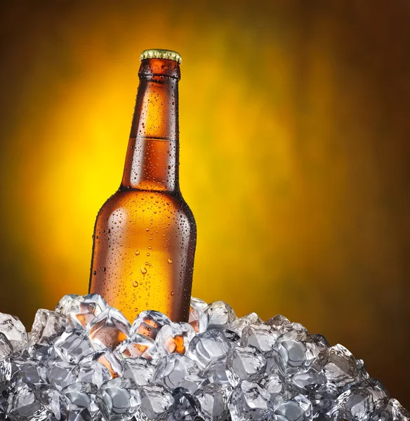 Garrafa fria de cerveja nos cubos de gelo no fundo amarelo . — Fotografia de Stock