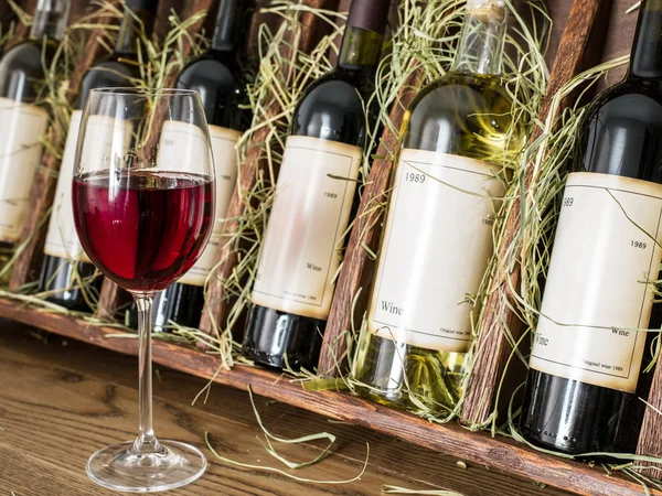 Glas rode wijn en wijn flessen op de achtergrond. — Stockfoto
