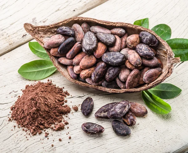 Cocao en polvo y granos de cocao en la mesa de madera . — Foto de Stock