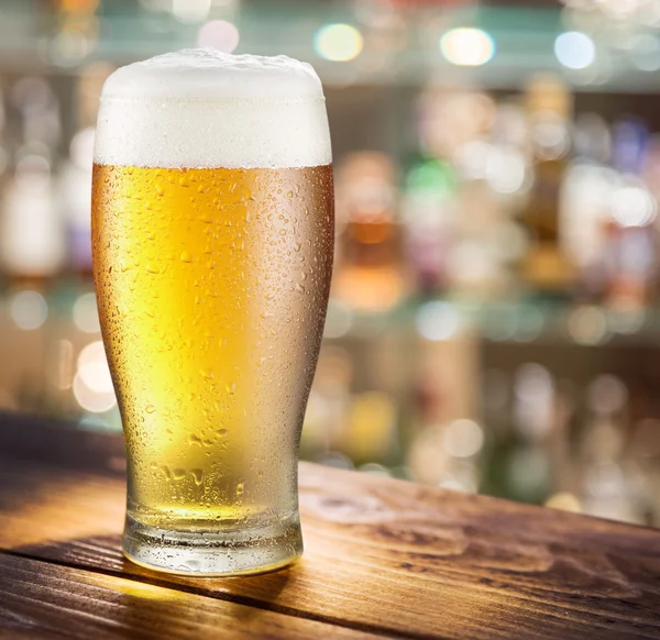 Glass of light beer on the glass bar counter. — Stock Photo, Image