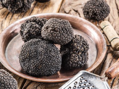 Eski ahşap masa üzerinde plaka üzerinde siyah truffles.