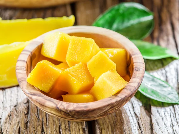 Owoce mango i pokrojone w kostkę mango na drewnianym stole. — Zdjęcie stockowe