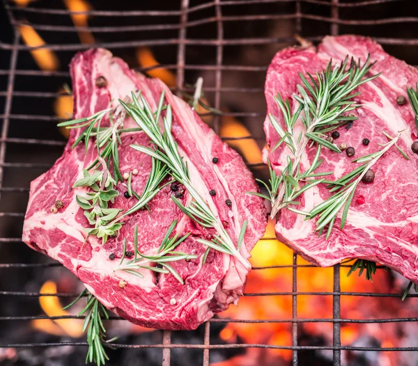 Filetes de costilla y parrilla con fuego ardiente detrás de ellos . — Foto de Stock