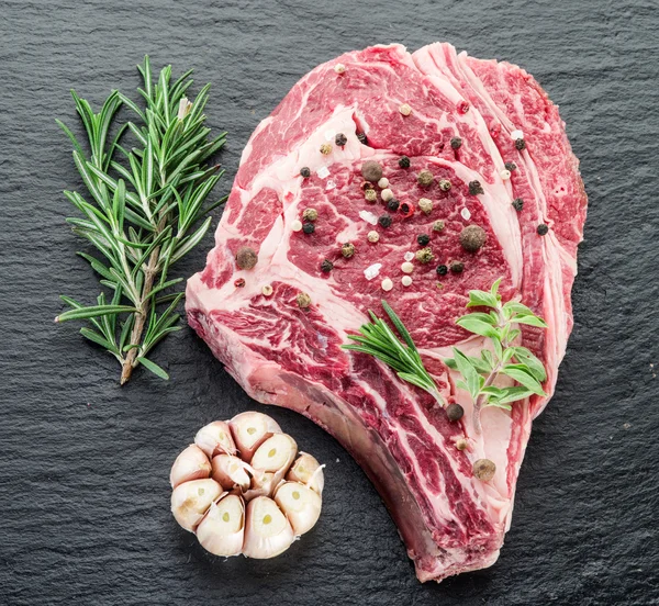 Rib eye steak with spices on the black background. — Stock Photo, Image