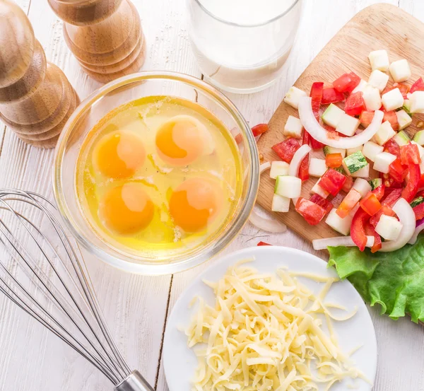 Omelet ingrediënten: eieren, vers gesneden groenten, melk en kaas op de houten tafel. — Stockfoto