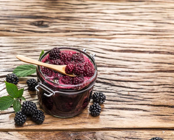 Blackberry confiture on old wooden table. Several fresh berries are near it. — Stock Photo, Image